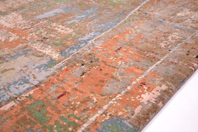 Detail of handwoven carpet with multicoloured wool and silk pile. with areas of terracotta and grey.