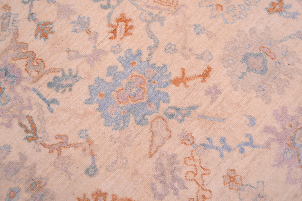 Detail of palmetts and Oushak motifs in central fields of hadnknotted carpet with terracotta and blues