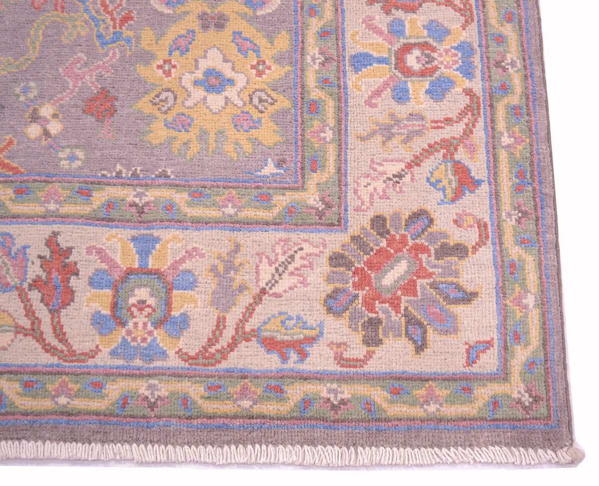 Corner detailing of Ushak / Oushak rug in grey and cream with cotton warp fringe and multipe floral motifs in field and border.