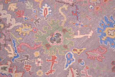 Detail of main central green palmette of handmade rug with various soft pastel hues in main soft grey field.