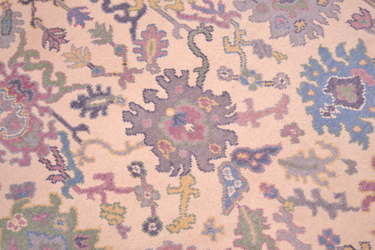 Handmade Oushak rug close-up of pastel floral pattern on cream background.