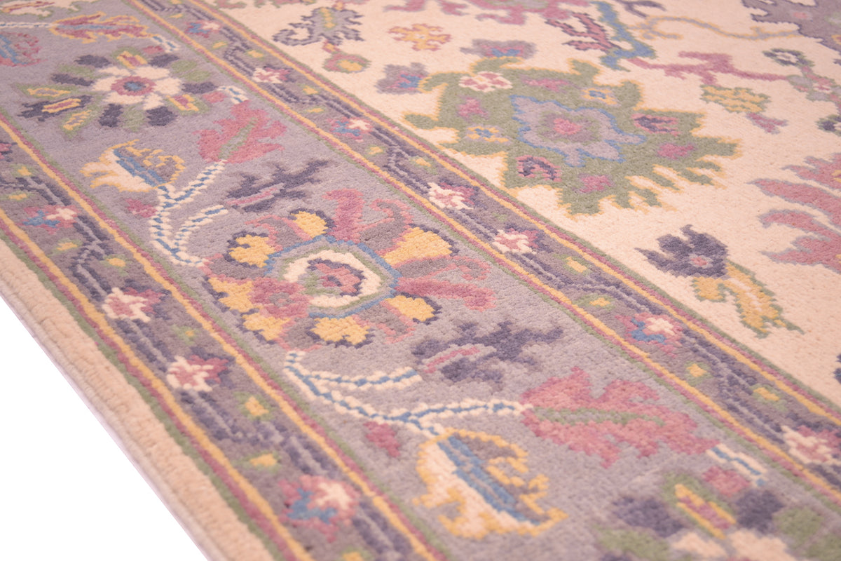 Handmade Oushak rug border close-up with mauve, blue, and gold ornamental bands.