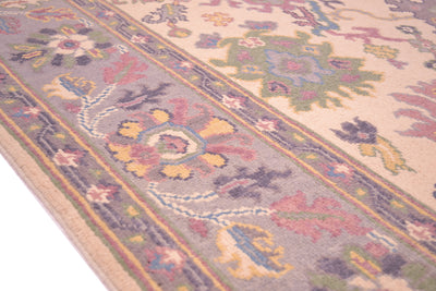 Handmade Oushak rug border close-up with mauve, blue, and gold ornamental bands.