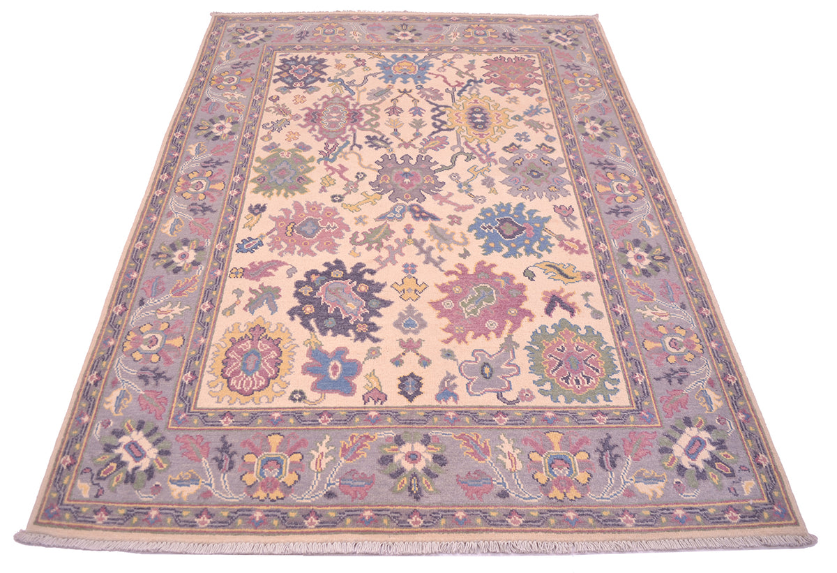 Handmade Oushak rug with central medallion, cream background and mauve-blue ornamental details.