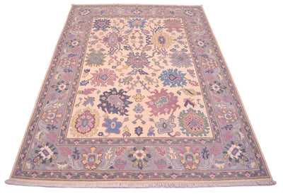 Handmade Oushak rug with central medallion, cream background and mauve-blue ornamental details.