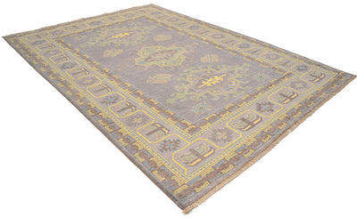 Corner view of grey Oushak carpet with yellow geometric detailing and thin border