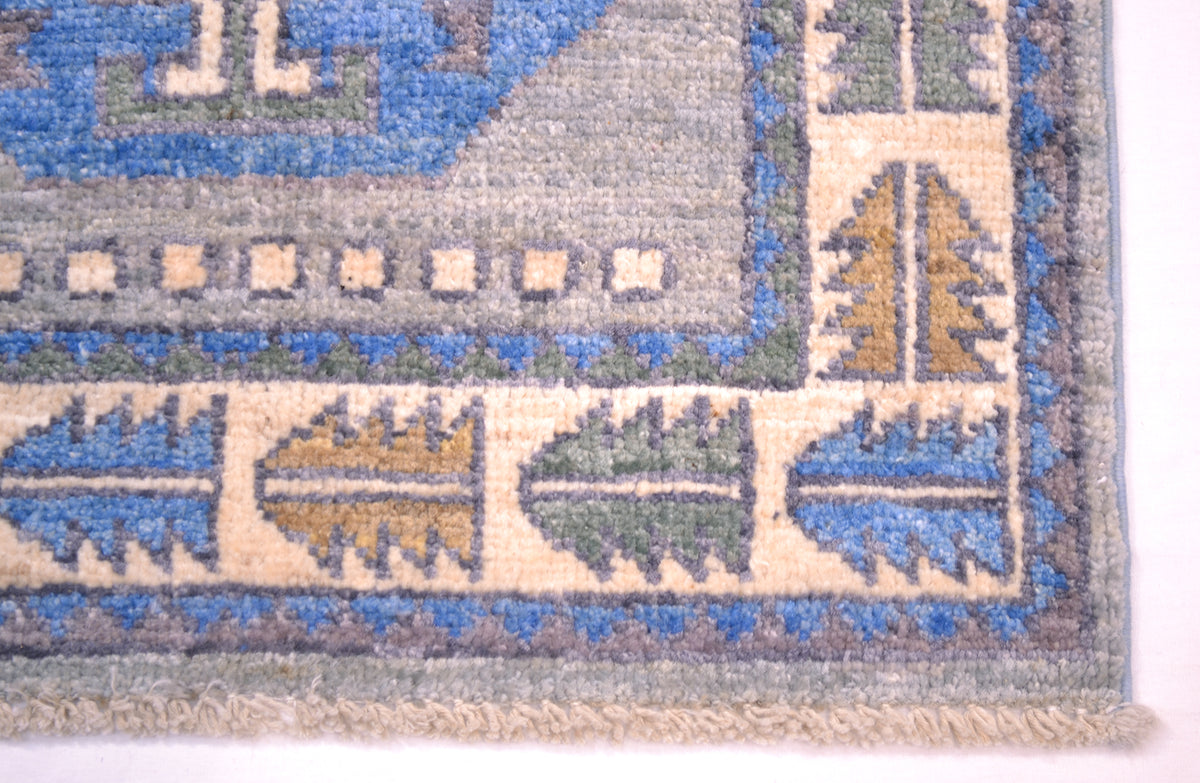 Corner detail of Oushak mat in blue and grey with geometric border.