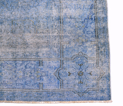 Corner detail of vintage blue overdyed carpet  with charocal outling the border lines of ghost like floral detailing in border and field. Vintage distressed-look pile.
