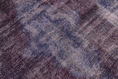 Close up and detail of main field and centralised motif of large vintage carpet with richly saturated tones of indigo and aubergine colouration. Handknotted with zero pile amd cotton warp foaundation. Overdyed vintage carpet with traditional design.