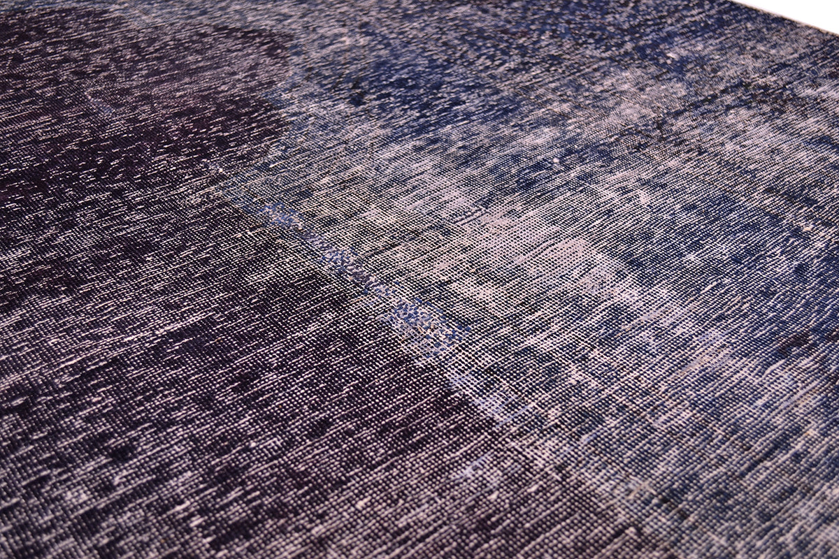 Close up and detail of main field of vintage carpet with zero pile and cotton warp and wefts. Shaved pile and re dyed with rich colouration of blue and aubergine.