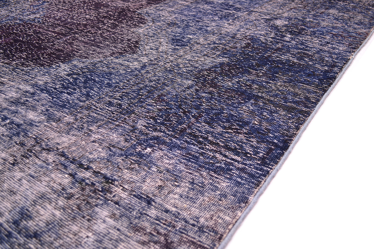 Side edge of large vintage iverdeyd carpet with an angled view on a white background. Neat light blue selvedge edges. Handknotted wih low pile/ zero pile in blues and indigos.