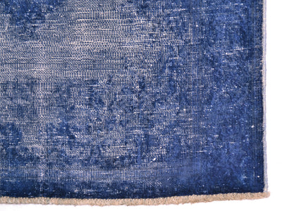 A close-up of a distressed blue runners corner showing its woven texture, faded pattern, and a fringed edge on a white background.