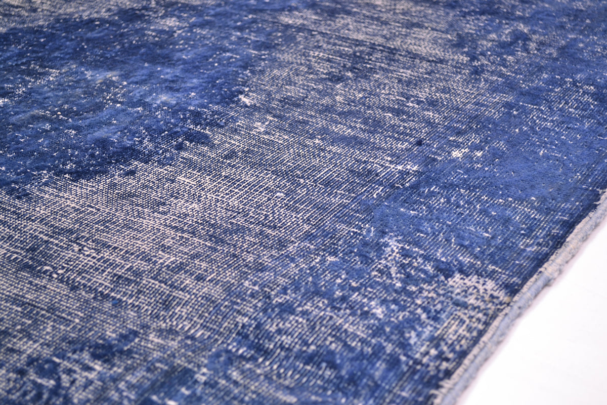 A close-up of a blue and white distressed area rug showing its woven texture and faded pattern.