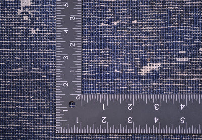 Close-up of a blue and white textured runner/rug with a metal ruler to indicate scale.
