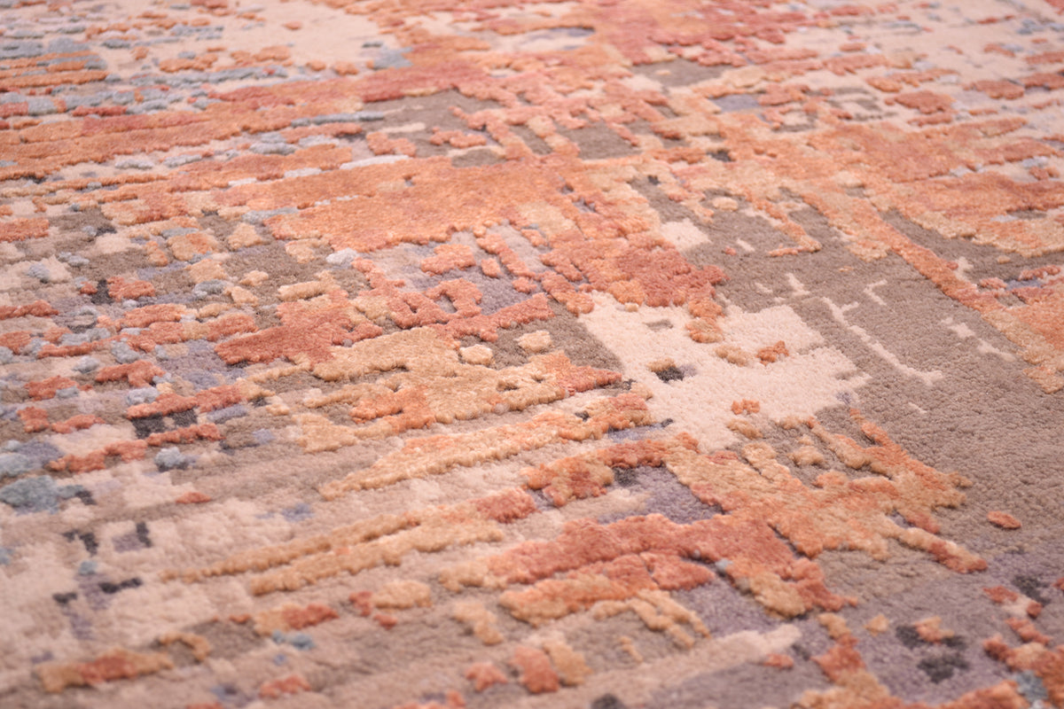 Detail showing texture of modern expressionistic carpet with raised silk highlights in gold and terracotta/light rust. with a grey and beige stone matte wool background/ base.