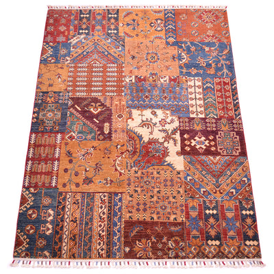 A 7x5 rectangular patchwork-style area rug with a traditional geometric and floral pattern, featuring a mix of rust orange, navy blue, burgundy red, beige, and cream blocks, finished with white fringe on the top and bottom.