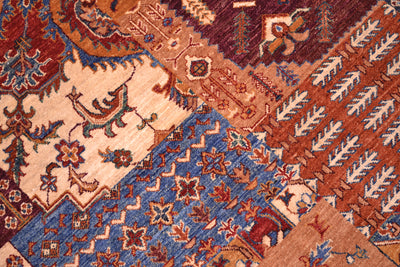 Close-up of a traditional patterned patchwork design rug with diagonal sections in cream, rust red, blue, and brown, featuring floral and geometric motifs.