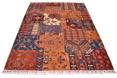 A rectangular Afghan patchwork-style area rug with an intricate multicolour geometric and floral pattern, featuring fringed edges on a plain white background.