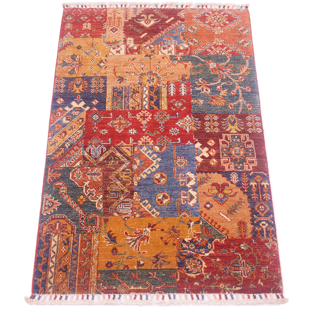 A 5x3 rectangular Afghan patchwork-style area rug with a multicolour geometric and floral pattern, featuring a red border and white fringe on the top and bottom, shown flat against a white background.
