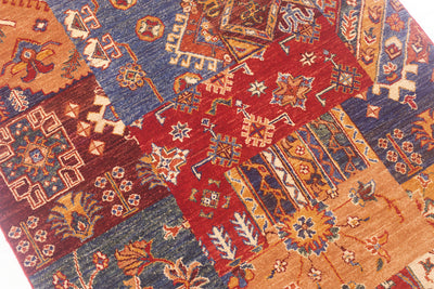 A close-up of a Afghan patchwork-style hand-knotted rug with multiple geometric and floral motifs in red, blue, tan, and brown tones.