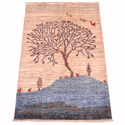 A rectangular handwoven pictorial Loribaft small rug featuring a stylized tree on a hill with small birds and animals, set against a light beige background with a blue textured lower section.
