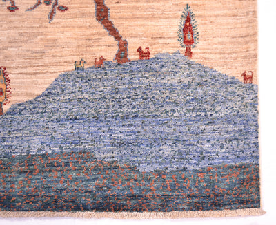 Close-up of a corner of a handwoven Loribaft small pictorial rug showing a stylized landscape with a blue hill, red and orange trees and animals, and a beige background.