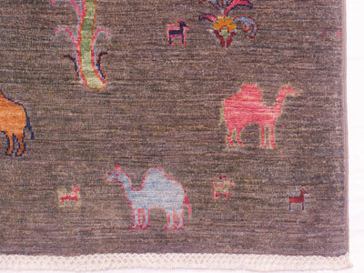 A close-up of a pictorial grey Loribaft runner with a dark grey textured background and stylised animal motifs including camels and a tree in pink, blue, orange, and green.