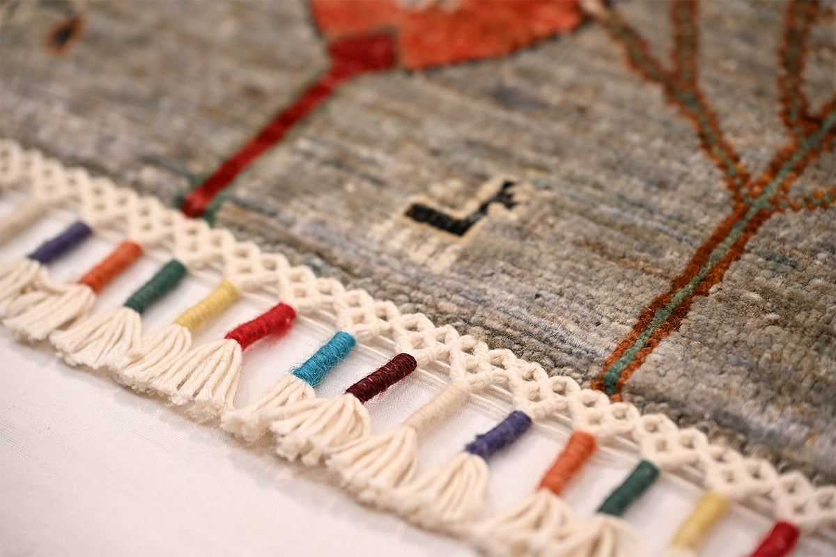 Grey Loribaft Afghan rug with woven tassel fringe in blue, red, green, and beige threads