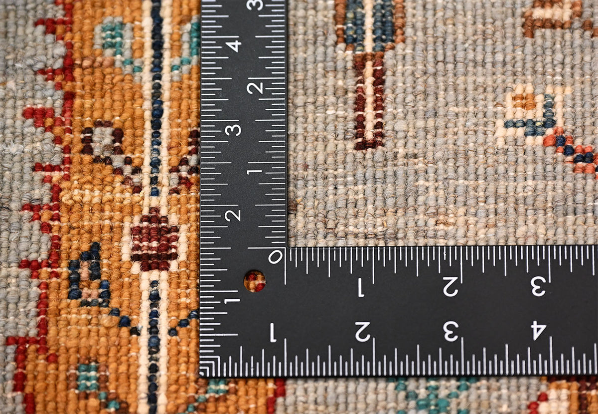 Pictorial Loribaft rug with tree design close-up showing weave detail beside ruler to show scale of the rugs knotting, tree motif in orange, blue, and red threads