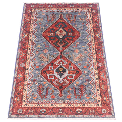 A traditional oriental Qashqai area rug with a red border, a blue field, and two large central diamond medallions in red, navy, beige, and orange.