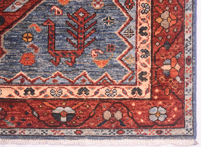 A close-up of a traditional patterned Persian style rug corner showing a blue field, red border, cream decorative bands, and small floral motifs.