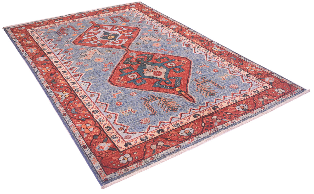 A traditional Persian-style handmade Qashqai design area rug with a light blue field, red borders, and central medallions, shown from an elevated angle on a white background.