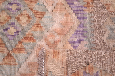Close-up of a woven soft coloured Afghan Kilim runner with a geometric pattern in beige, orange, purple, and grey, showing the texture of the pile and a fringed edge.