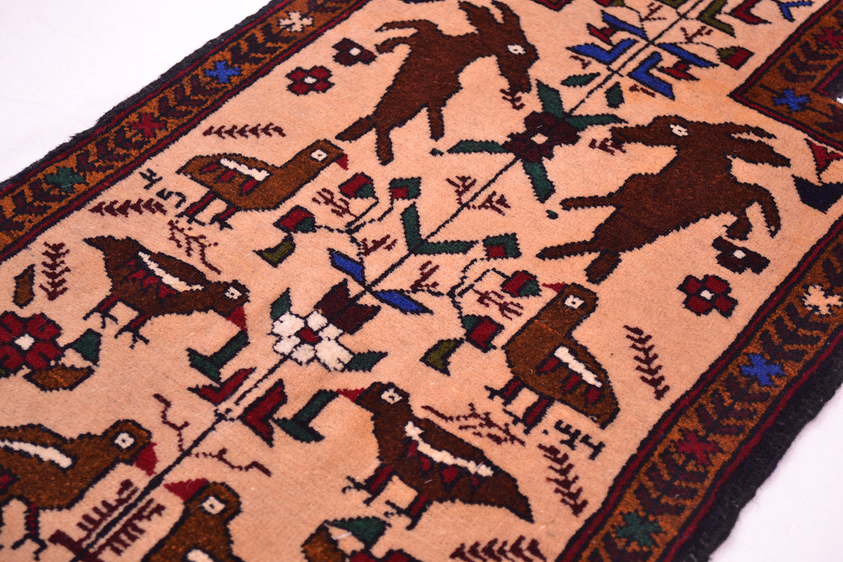 A close-up of a handwoven Afghan Belouch Salt bag face with a beige background and dark brown animal motifs, including deer and birds, surrounded by a patterned border with blue, green, and red accents.
