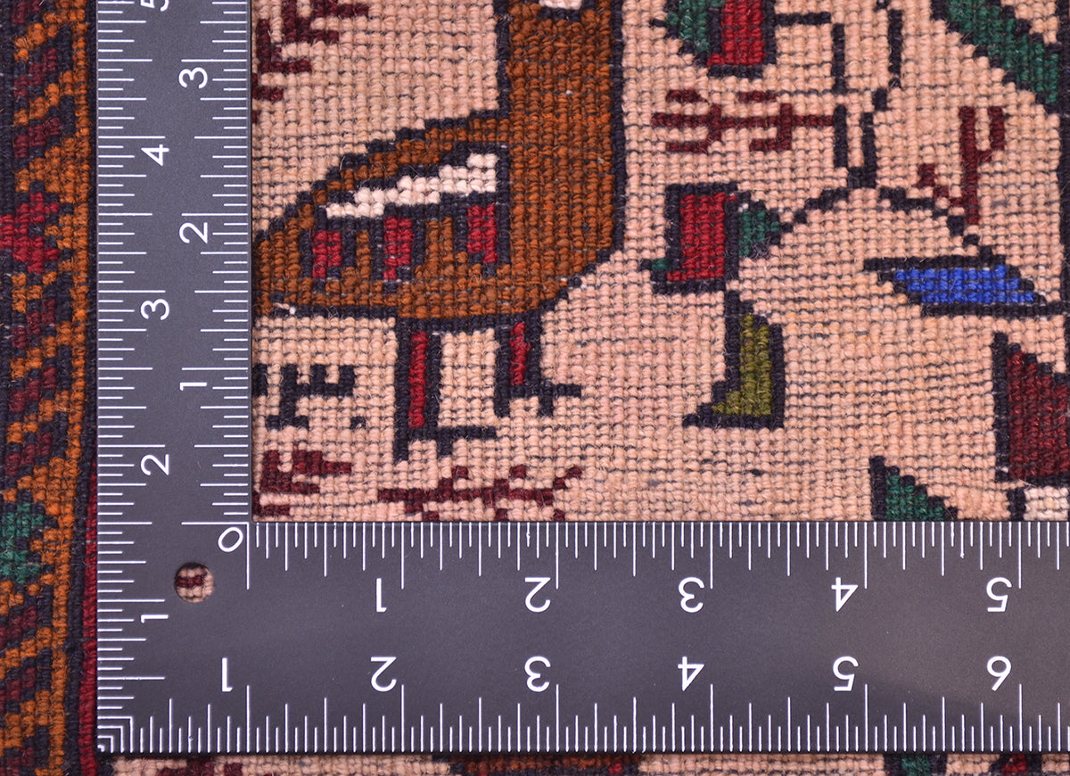 Close-up of the hand-knotted weave of a Belouch Salt bag face mat/ rug pattern in beige, brown, red, green, and blue, shown with a metal ruler to show scale of the knotting.