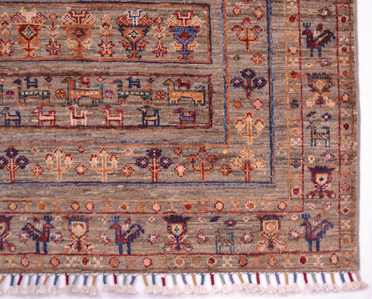A close-up of a traditional handwoven modern Afghan Samarkand rug with a beige-gray base and multicolour geometric and animal motifs, finished with a fringed edge.
