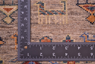 Close-up of the hand-knotted weave of a patterned fine Afghan Samarkand rug with a dark L-shaped metal ruler placed along the corner to show the quality and density of the knotting. 