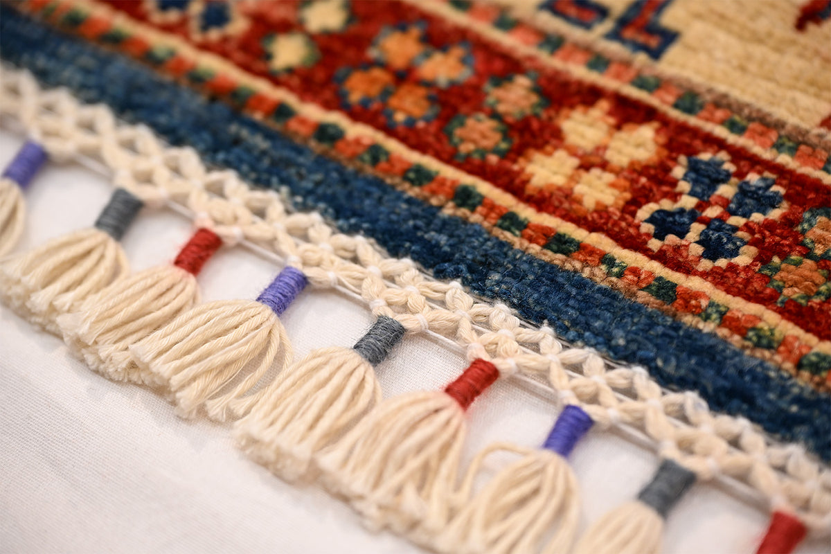 Close-up of rug fringe trim with cream tassels and multicolor edge stripes