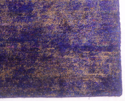 A close-up of a Sari Silk rug showing a mottled pattern of deep purple, blue, and tan/beige tones.