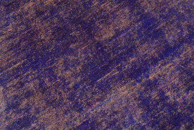 A close-up of a textured surface of a handmade Sari Silk rug with a mottled blend of deep purple and warm brown tones, resembling a painted or brushed material sample.