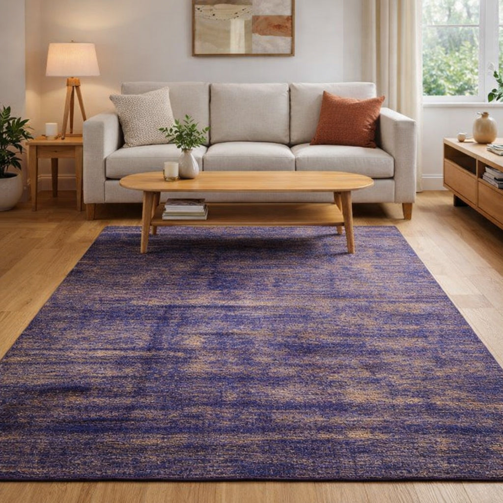 AI generated image: A rectangular Handmade Sari Silk area rug in a purple-blue and beige distressed pattern, shown in a modern living room setting with a light wood coffee table, beige sofa, and wooden flooring.