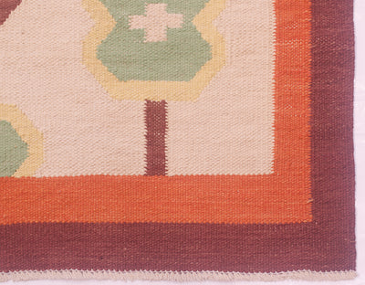 Close-up of an Afghan woven Scandi Kilim rug corner showing a cream field, orange border, dark brown border, and green and yellow geometric motifs.