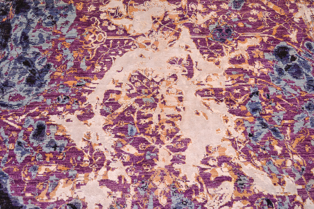Centre design detail from handmade abstract Seismic carpet with sky blue, to mid blue detailing and areas of mauve with vestiges of a traditional vine and floral pattern interrupted with larage areas of golden white vicose silk.