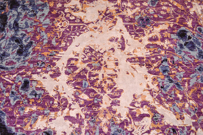 Centre design detail from handmade abstract Seismic carpet with sky blue, to mid blue detailing and areas of mauve with vestiges of a traditional vine and floral pattern interrupted with larage areas of golden white vicose silk.