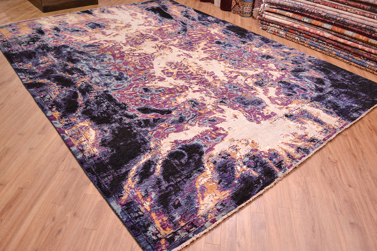 Angled view of Abstract Carpet with dramatic elements of abstraction of  traditional design ignited with areas of gold/yellow white art vicose silk with reflective properties. Fluidity of design. Indigo, black, mauve, light and mid blue wool pile.