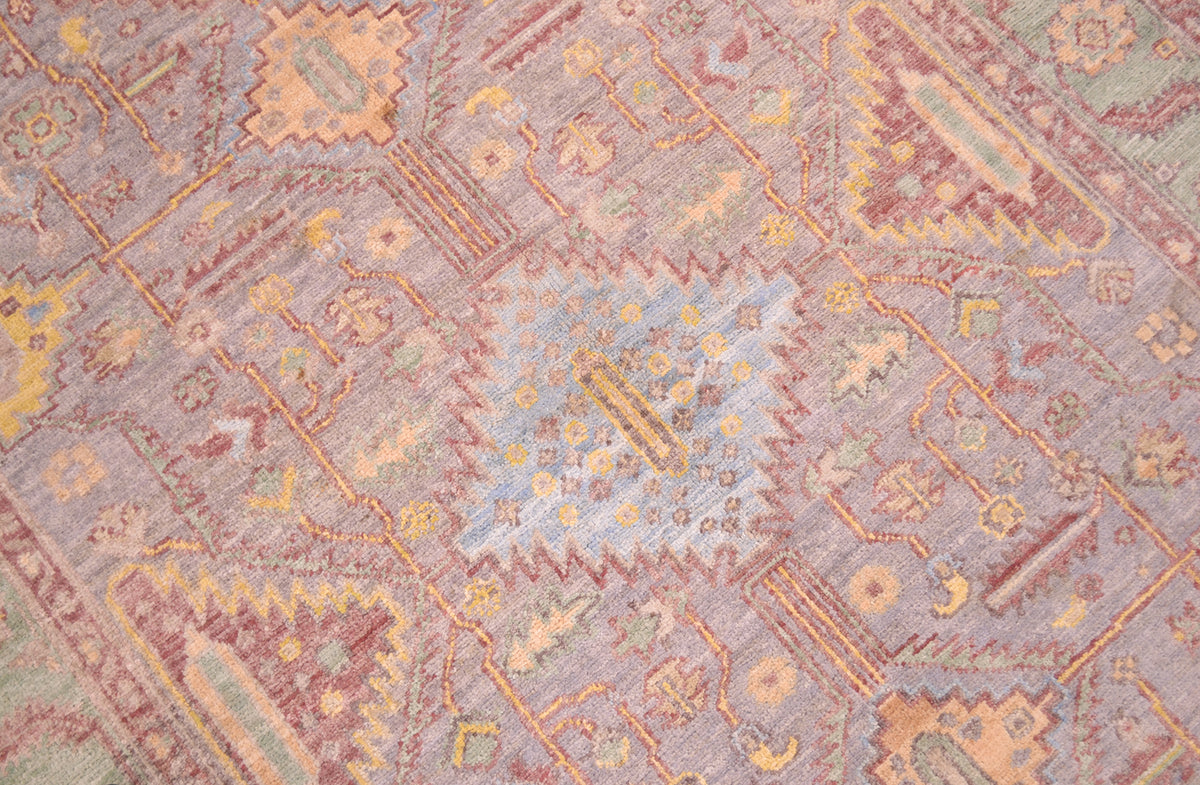 Close up detail of central device of Afghan Serapi rug with light blue central serrated medallion motif surrounded by a geometric network of stylized leaves and flowers adn yello detailing.