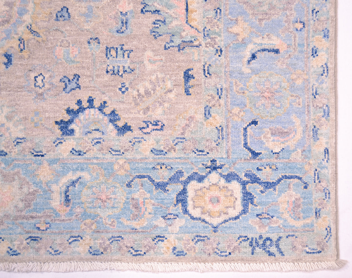 Detail of corner of rug  with cream, blue and grey motifs and stylized leaves and boteh. Hand knotted with natural vegetable dyes with soft pastel colour combinations.