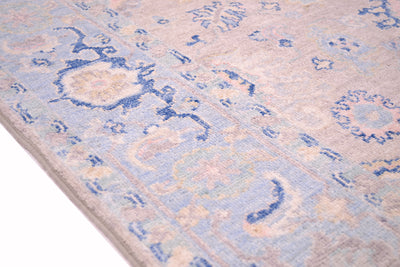 Detail of border of handknotted rug with light blue and duck egg coloured border background with cloudband pattern border and stylized leaves. Soft pastel tones throughout the colouration of this rug.