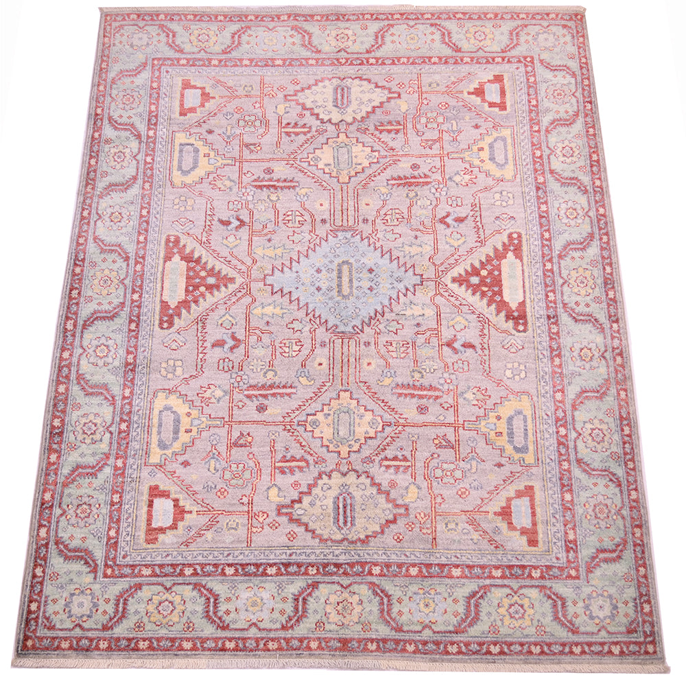Over all view of geometric hadnmade rug with geometric framwork with angular leaves and stylized flowers.  Serrated medallions fill the field and centralised light blue diamond medallion. 