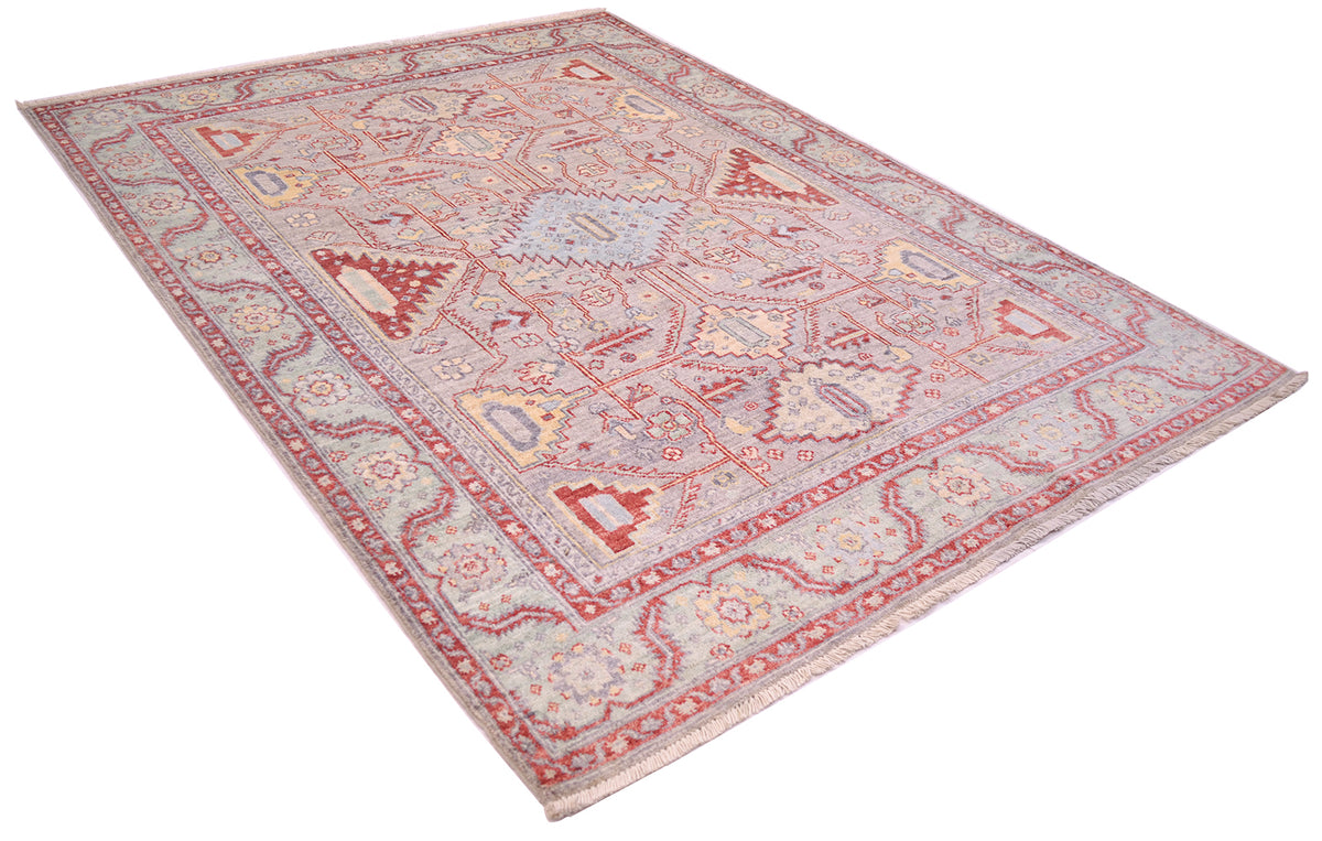 Angled view of serapi design rug with meander border with stylized angular leaves and rosettes. The border background is a soft green colouration. Pure wool pile on a cotton foundation.
